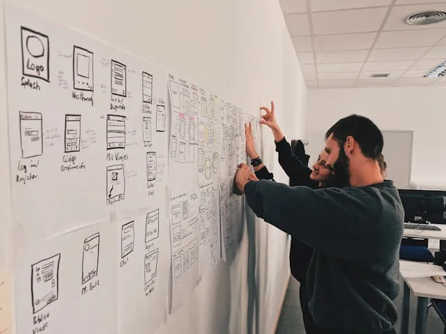 Designers mapping out app screens across a wall of wireframes